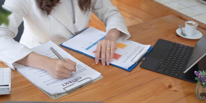 Business woman using calculator and laptop for do math finance on wooden desk in office and business working background, tax, accounting, statistics and analytic research concept.