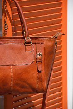 close-up photo of orange leather bag on a wooden blinds. outdoors photo