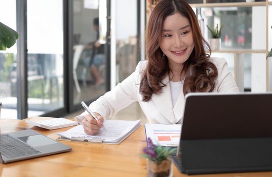 Young Asian businesswoman is happy to work at the modern office using a tablet..