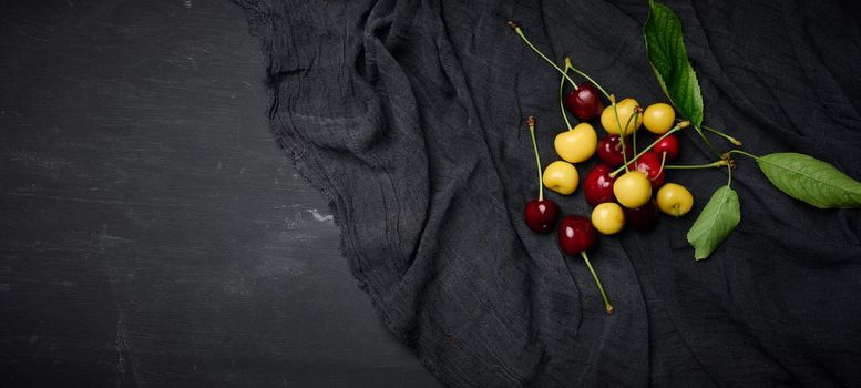 Ripe red and yellow cherries on a black background. summer berry, top view