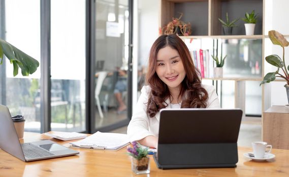 Asian businesswomn sitting working at the office. Looking at camera..