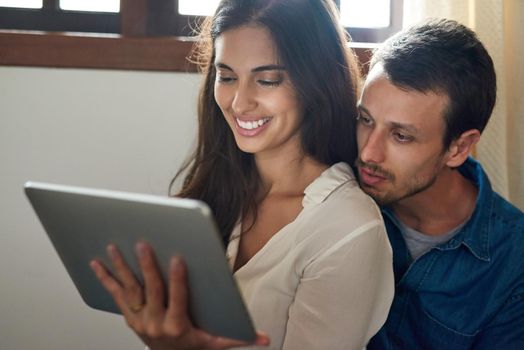 Spending our day watching some videos online. an affectionate young couple using a digital tablet together at home