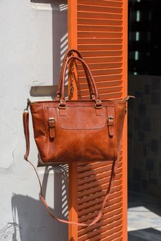 close-up photo of orange leather bag on a wooden blinds. outdoors photo