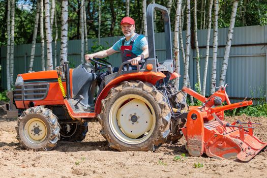 A man on a mini-excavator levels a piece of land, loosens the soil