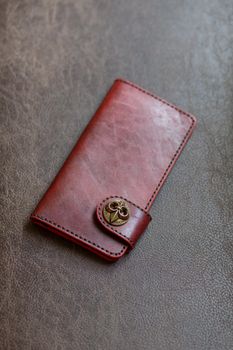 Brown natural leather women wallet on dark leather background.