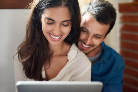 Watching some of our favorite videos together. an affectionate young couple using a digital tablet together at home