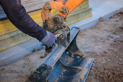 A man repairs a tractor bucket, changes the mounting sleeve. Replacing the nozzle on the tractor boom. Close-up