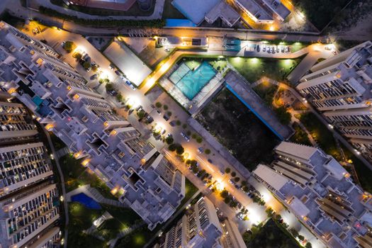 aerial drone shot ooking down over skyscrapers of a premium apartment complex with parking swimming pools with lights switched on at dusk twilight in gurgaon haryana India drone shot