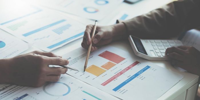 Close up of accountant working and analyzing financial reports project accounting with chart graph and calculator in modern office : finance and business concept..