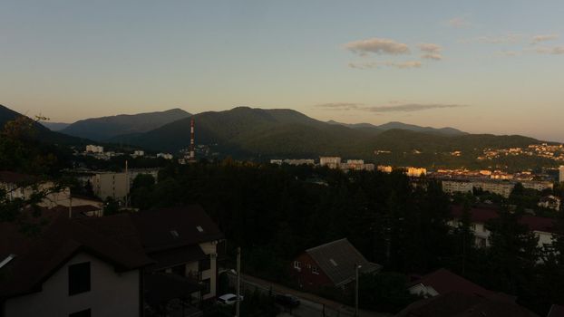 LAZAREVSKOE, SOCHI, RUSSIA - MAY, 27, 2021: Panorama of sunset in the mountains. A magical view of the sea and small town from the observation deck.