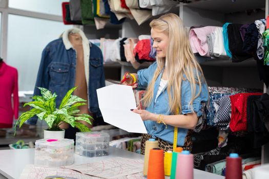 A young girl in a tailor's shop shapes a tailor's mold and adjusts it to fit the size of her next blouse. Blonde with long straight hair.