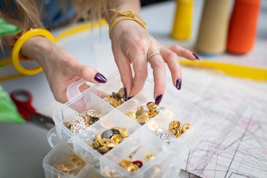 The seamstress chooses from among the many decorative buttons the one that will fit best. At the back of the tailor's workshop.