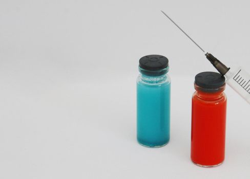 Two Vials of medicine for injection and a syringe. Two ampoules with covid-19 vaccine and a syringe on a white background.