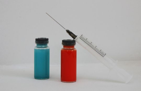 Two bottles of blue and red medicine and a syringe to enhance immunity.