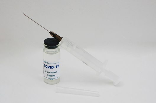 Ampoule with covid-19 vaccine and syringe on a white background.