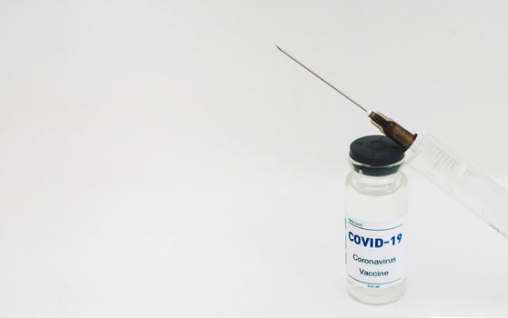 Glass ampoule with a vaccine and a plastic syringe with a needle on a white background.