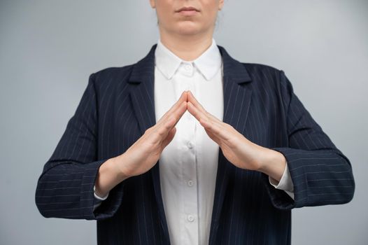 Business woman in a suit holding her hands in the shape of a house