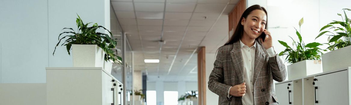 Asian business woman making a phone call and smiling at office. High quality photo