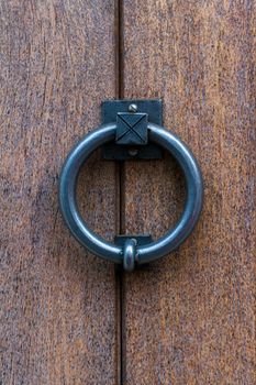 Metal ring door knocker on a wooden door close up