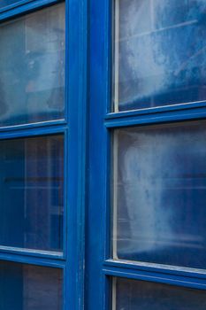 Blue wooden double door with glass windows closed shutters close up