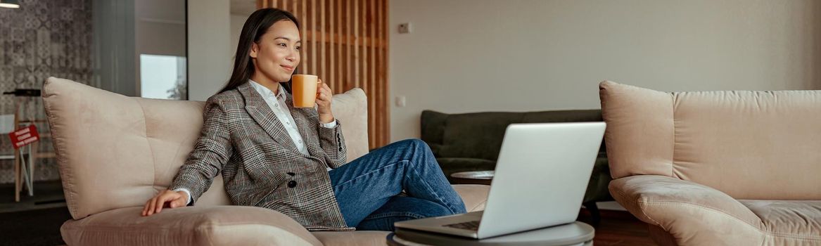 Asian business woman working laptop and drink coffee sitting in cozy cafe. High quality photo