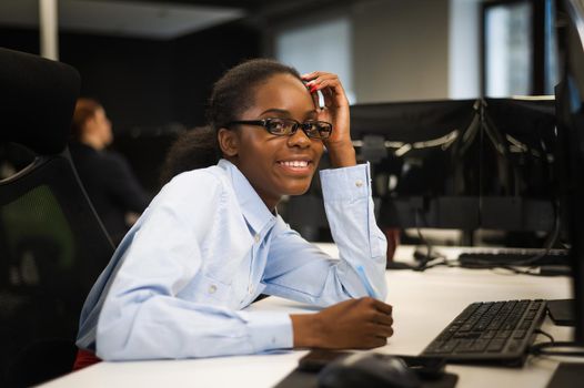 African young woman typing on a computer at her desk in the office