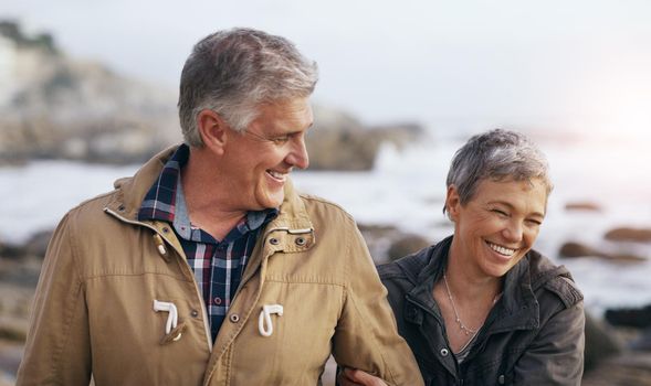 Just like the good old days. a beautiful elderly couple taking a walk at the beach