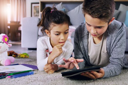 Learning is as easy as one, two, tap. a brother and sister using a digital tablet together at home