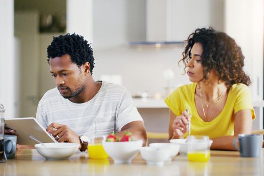 Whos that woman in that picture you just scrolled through. a young couple using a digital tablet together while having breakfast at home