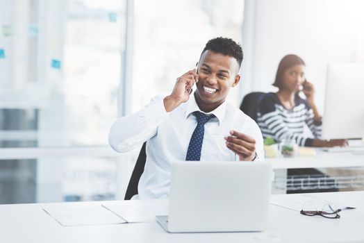 Good news always keep on coming when you work hard. two young businesspeople sitting at their office desks making phone calls