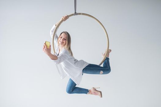 Caucasian woman gymnast on an aerial hoop takes a selfie on a smartphone