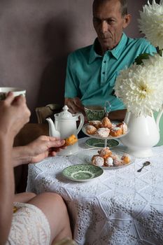 tea break in the English style, still life with flowers and donuts in the morning sun, homemade cakes, married couple drinking tea together at breakfast in english style, beautifully set table