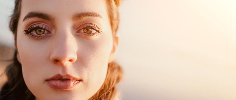 Closeup portrait of sensual young brunette woman in red dress, happily dancing outdoors isolated on blurry sea background with natural bokeh in soft warm sunset backlight. Selective focus.