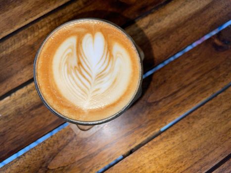 beautiful cup of cappuccino coffee with latte art in the wooden space background