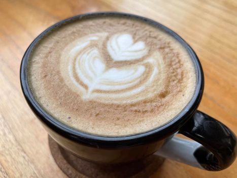 beautiful cup of cappuccino coffee with latte art in the wooden space background