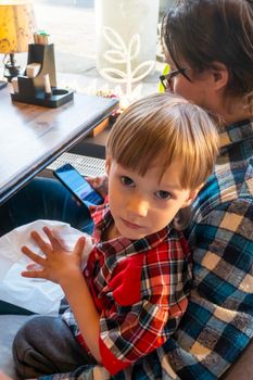 a child with his father in a restaurant draws a coloring book, waiting for cooking