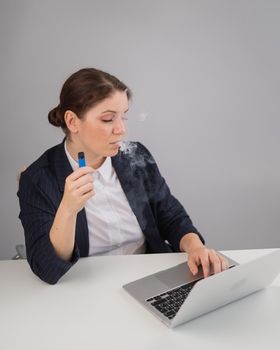 Business woman smoking a disposable vape while sitting at her desk