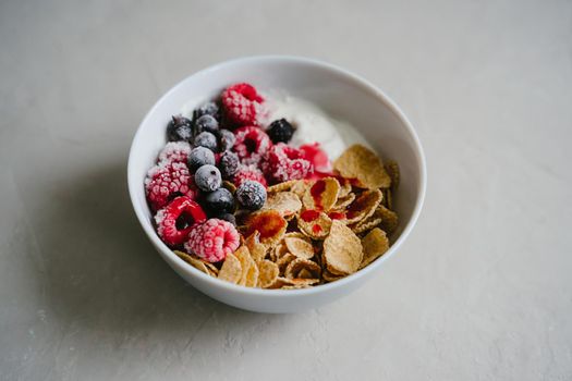 Healthy breakfast with berries, cereals and natural yogurt. Multi-lacquered cereals for breakfast. Berries in ice. Frozen raspberries and black currants. Delicious and healthy breakfast.