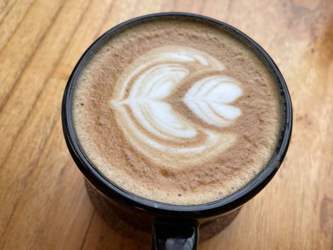 beautiful cup of cappuccino coffee with latte art in the wooden space background