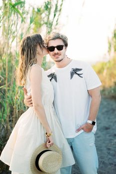 Girl kissing on the cheek of a guy in sunglasses. High quality photo