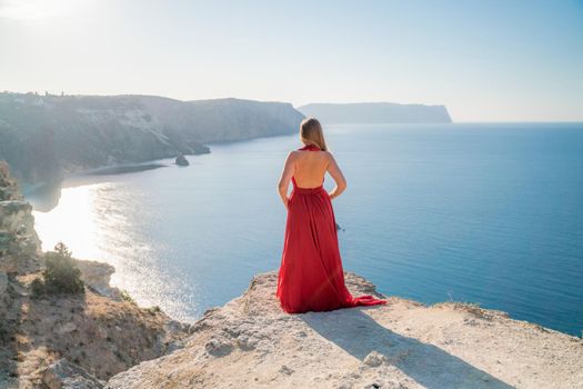 A woman in a red flying dress fluttering in the wind, against the backdrop of the sea