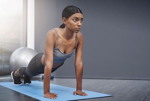 Every decision in the end involves balance and sacrifice. an attractive young woman busy doing stretching exercises on her gym mat at home