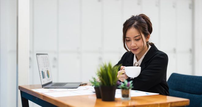business woman or accountant working on calculator to calculate business data, accountancy document and laptop computer at office, business concept.