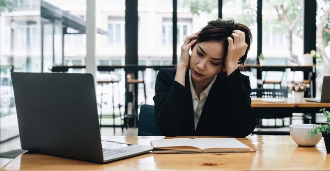 Tired asian business woman with headache at office, feeling sick at work.