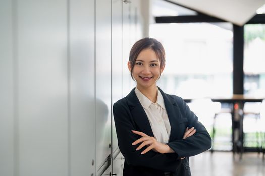 Portrait of smiling confident aisan female with arms crossed standing in office.