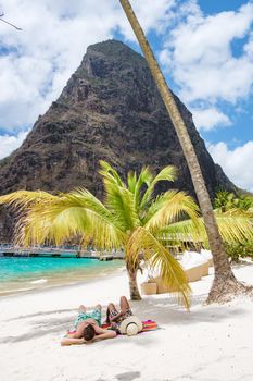 couple sunbathing on the beach during summer vacation on a sunny day, men and woman on vacation at the tropical Island of Saint Lucia Caribbean. Sugar beach St Lucia Caribbean