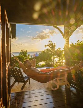 Young men in swim shorts sunbathing in a hammock at Saint Lucia Caribbean, men at infinity pool during sunset. man in swim shorts at the pool