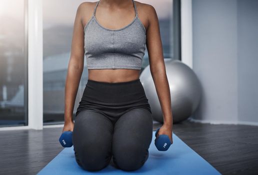 Strength is measured in time not weight. an unrecognizable young woman on her knees holding dumbbells while exercising on her gym mat at home