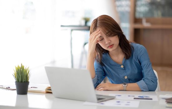 Image of an Asian woman who is tired and overthinking from working with a tablet at the office..