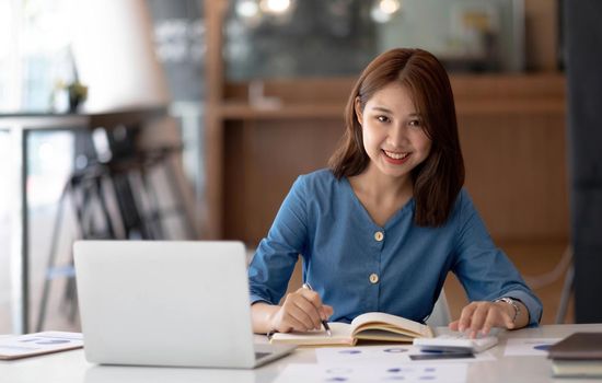 Young beautiful woman using her laptop while sitting in a chair at her working place, Small business owner people employee freelance online sme marketing e-commerce telemarketing concept..